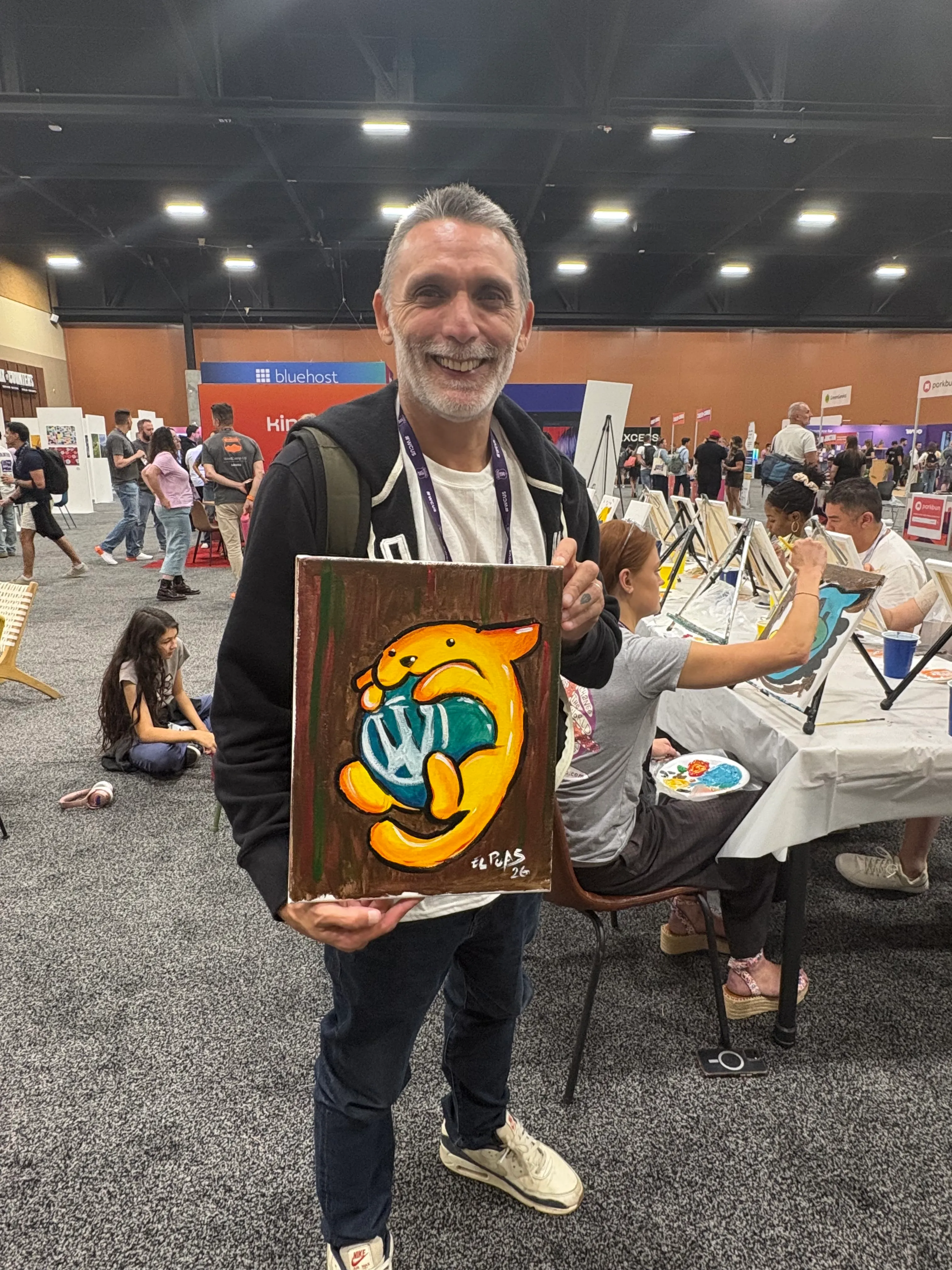 Alfredo Navas holding the Wapuu artwork he painted during a creative activity at WordCamp US 2026.