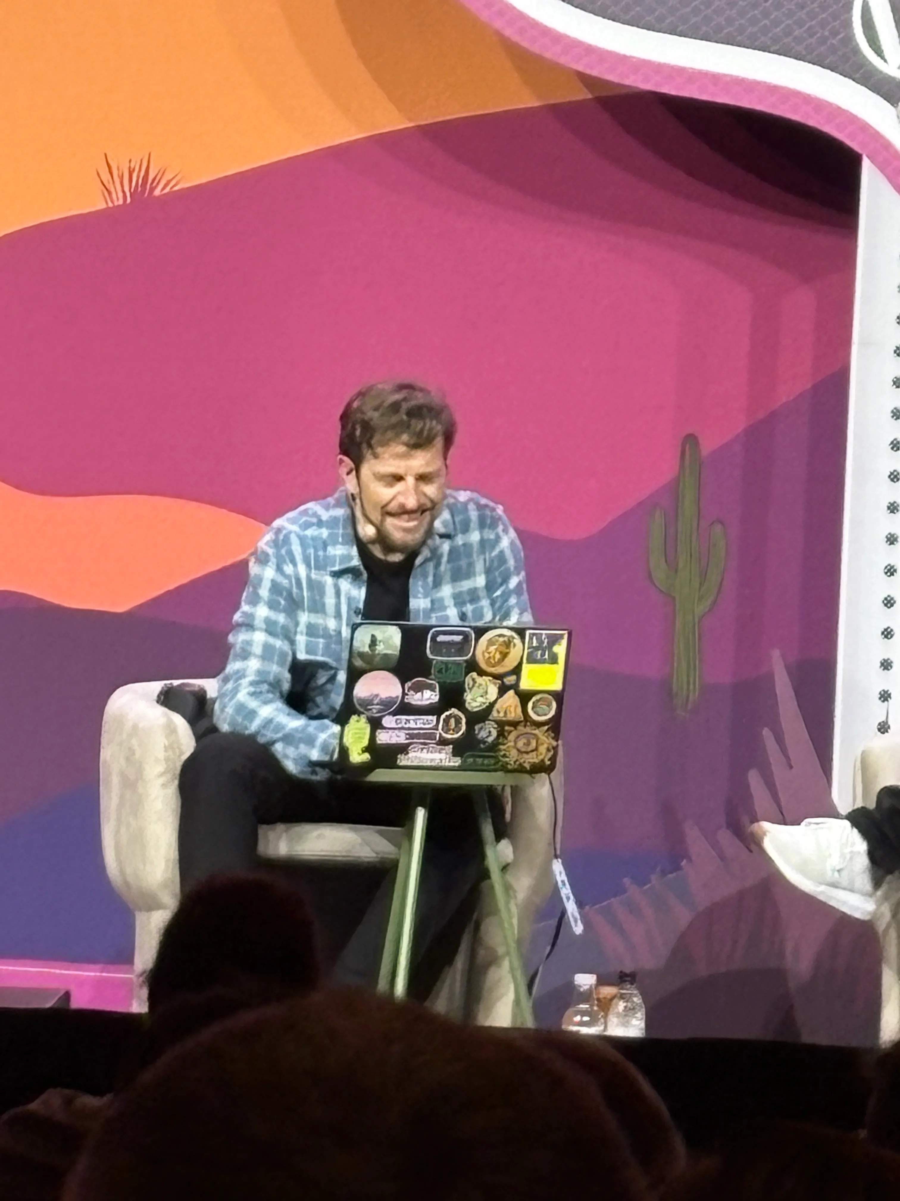 Matt Mullenweg seated onstage with a laptop during the closing of WordCamp US 2026.